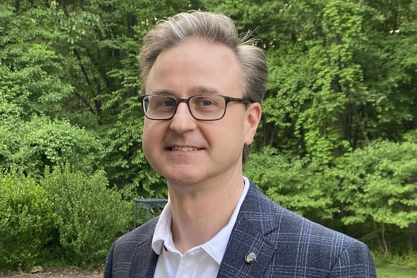 Image of blonde, white male with glasses in front of tree